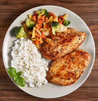 Grilled chicken breast served with steamed broccoli, mixed vegetables, and fluffy white rice, garnished with fresh basil on a neutral plate.